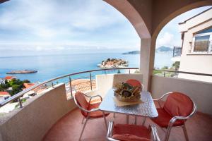 a table and chairs on a balcony with a view of the ocean at Apartments Baron in Sveti Stefan