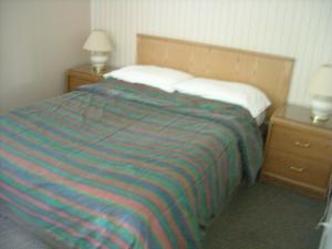 a bed with a striped blanket and two night stands at Motel le Verseau in Sorel