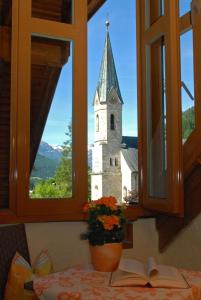 una ventana con vistas a una iglesia desde una mesa con un libro en Dachstein West Hotel GmbH-Kirchenwirt Russbach en Russbach am Pass Gschütt