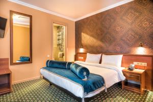 Habitación de hotel con cama grande y espejo en Golden Tulip Borjomi en Borjomi