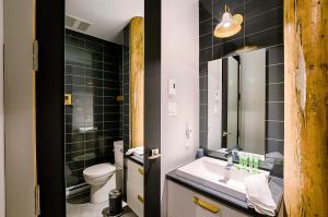 a bathroom with a sink and a toilet and black tiles at Les Lofts Champlain - Par Les Lofts Vieux-Québec in Quebec City