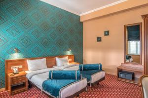 a hotel room with two beds and a green wall at Golden Tulip Borjomi in Borjomi