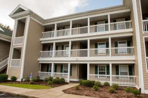 un gran edificio de apartamentos con balcones y arbustos en Pawley's True Blue en Pawleys Island