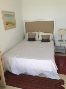 a bed with white sheets and pillows in a bedroom at Appartement - Vue sur Mer- Hammamet in Hammamet