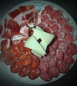 eine Platte mit Fleisch und Käse auf dem Tisch in der Unterkunft Hostal Rural La Casa Verde in Cheles