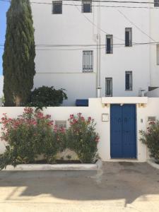 a building with a blue door and flowers at Appartement - Vue sur Mer- Hammamet in Hammamet