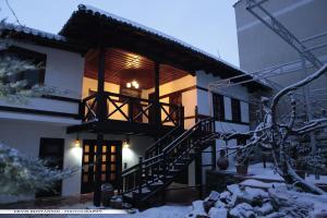 a house with a staircase in the snow at Guest House Bujtina Leon in Korçë