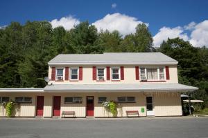 a red and white building with benches in front at Sunset Motor Inn in West Lebanon