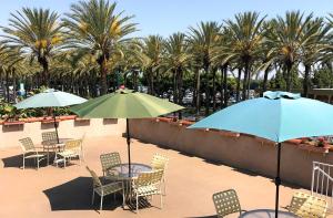 a patio with tables and chairs with umbrellas and palm trees at Kings Inn Anaheim at The Park & Convention Center in Anaheim