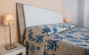 a bed with a blue and white comforter and a lamp at La Castellese in Aci Castello