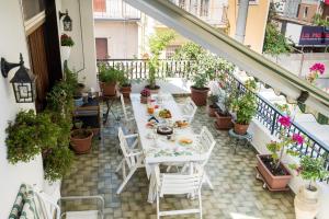 a table and chairs on a balcony with potted plants at La Castellese in Aci Castello