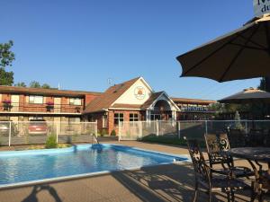 a swimming pool with a table and an umbrella at Motel Du Fleuve in Brossard