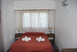 a bedroom with a red bed with two white pillows at Hotel Los Historicos in Villa Gesell