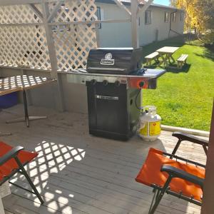 a grill sitting on a patio with two chairs at Grizzly Motel in Swan Hills