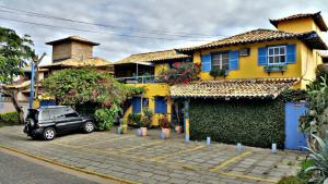 a black car parked in front of a yellow house at Pousada Repouso do Guerreiro in Búzios