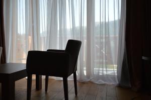 a chair sitting in front of a window with white curtains at Apartments B&P in Jahorina