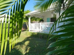 a house with a white porch and palm trees at La petite kaz in Saint-François