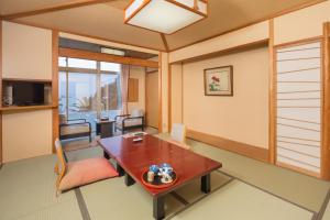 a living room with a table and a dining room at Dogashima Onsen Hotel in Nishiizu