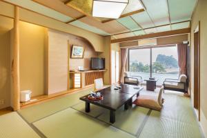 a living room with a coffee table and a large window at Dogashima Onsen Hotel in Nishiizu