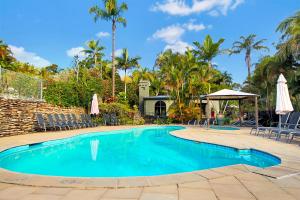 una piscina con sedie e ombrelloni di Korora Bay Village Resort a Coffs Harbour