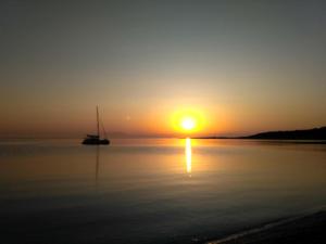 ein Boot im Wasser mit Sonnenuntergang im Hintergrund in der Unterkunft 9 Musses Studios in Skala Mistegnon
