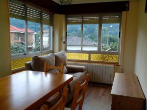 a living room with a table and a couch and windows at Toño el Alguacil in Selaya
