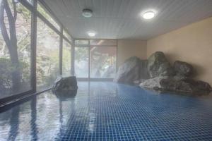 a room with a swimming pool with rocks in it at Hotel Heian in Fuefuki