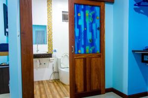 a bathroom with a toilet and a wooden door at i-Style Lanta Boutique House --- SHA Extra Plus in Ko Lanta