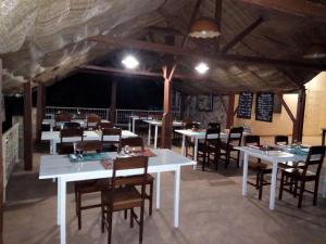 uma sala de jantar com mesas brancas e cadeiras de madeira em Hotel Chez Fanny em Palimé
