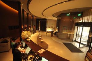a lobby of a building with two people at a counter at Goldmet Inn Changzhi Bayi Square in Changzhi