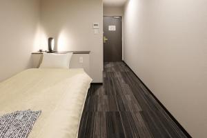 The Premium Hotel In Rinku في إيزوميسانو: غرفة صغيرة بها سرير وباب
