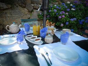 - une table avec des assiettes, des tasses et des boissons dans l'établissement Chambres d'Hôtes Le Crouzat, à Empurany