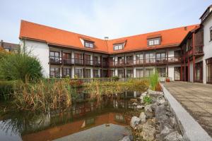 an apartment building with a pond in front of it at Hotel Garni Gästehaus am Mühlbach in Ottobeuren