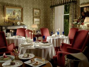 una sala da pranzo con due tavoli e sedie rosse di Inverlochy Castle Hotel a Fort William