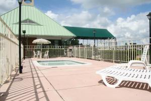 a patio with a pool and chairs and a fence at Days Inn by Wyndham Petersburg/South Fort Lee in Petersburg