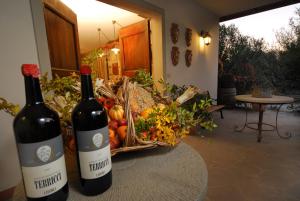 Agriturismo Borgo dei Ricci في إمبرونيتا: زجاجتان من النبيذ تقعان على طاولة مع سلة من الفواكه