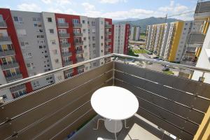 einen Balkon mit einem weißen Tisch und einige Gebäude in der Unterkunft Apartamente Olivero in Braşov