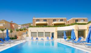 uma piscina com cadeiras e guarda-sóis azuis em Aegean Dream Hotel em Karfas