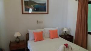 a bedroom with a bed with orange and white pillows at Maison Belle Baie in Baie Sainte Anne