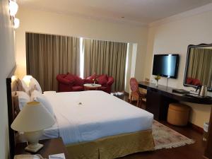 Cette chambre comprend un grand lit et une télévision. dans l'établissement Al Jawhara Metro Hotel, à Dubaï