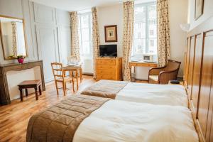 a bedroom with a bed and a desk and a television at Appart Hotel Charles Sander in Salins-les-Bains