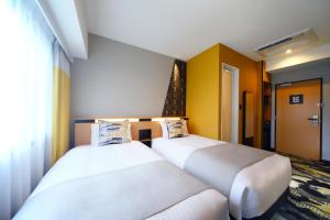 two beds in a room with yellow walls at Kyoto Tower Hotel Annex in Kyoto
