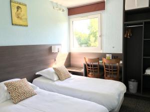 a hotel room with two beds and a table and a window at Les Orchidées , Hôtel & Restaurant in Verdun-sur-Meuse