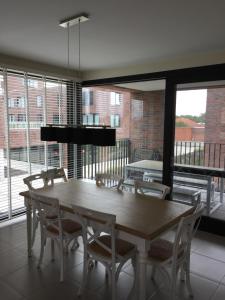 a dining room with a table and chairs and windows at Voeten in het zand in Ostend