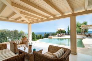 um pátio exterior com uma piscina, uma mesa e cadeiras em Seascape Villa em Porto Heli