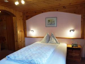 1 dormitorio con 1 cama blanca y 2 almohadas en Alpine Budget Rooms by Täscherhof en Täsch