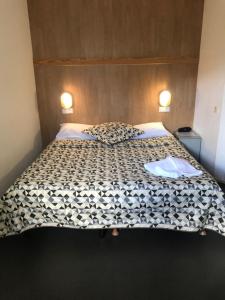 a bed with a black and white comforter on it at Hôtel Noctuel Blois Sud in Saint-Gervais-la-Forêt
