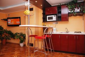 una cocina con armarios rojos y una barra con taburetes en VIP Apartments 11 Kiev en Vyshhorod