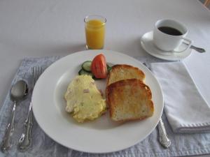 a white plate with eggs and toast and a cup of coffee at Gîte Les Acres Tranquilles B&B in Port-Daniel