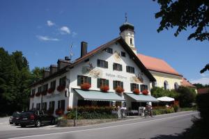 a large white building with flowers in front of it at Gasthaus Fischerrosl in Münsing am Starnberger See